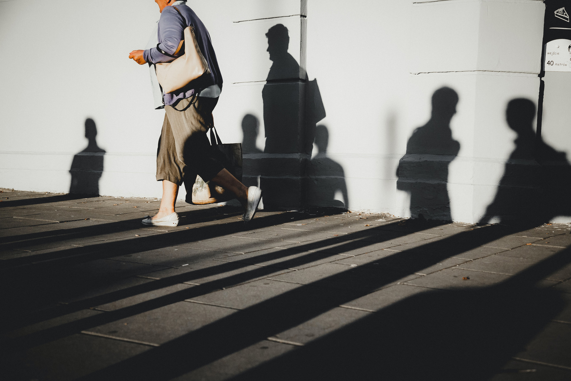 Shadows of people walking on the side of a building.